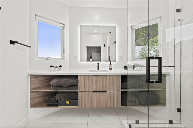 bathroom featuring tile patterned floors, a wealth of natural light, a shower with door, and vanity