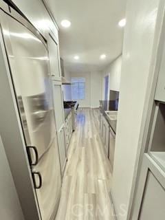 kitchen with light hardwood / wood-style flooring, white cabinetry, and stainless steel refrigerator