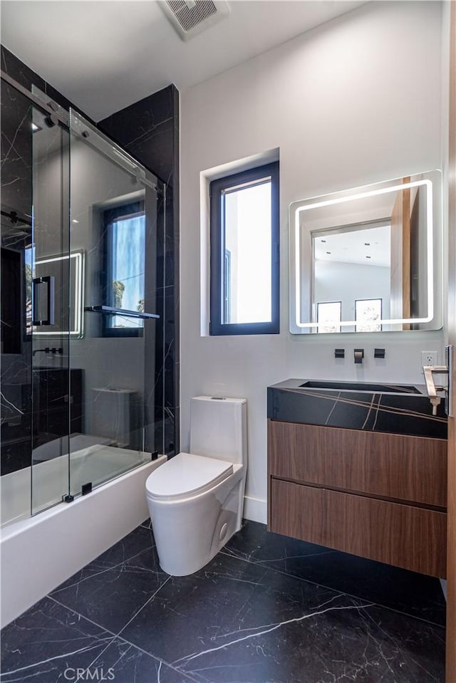 full bathroom featuring vanity, combined bath / shower with glass door, and toilet