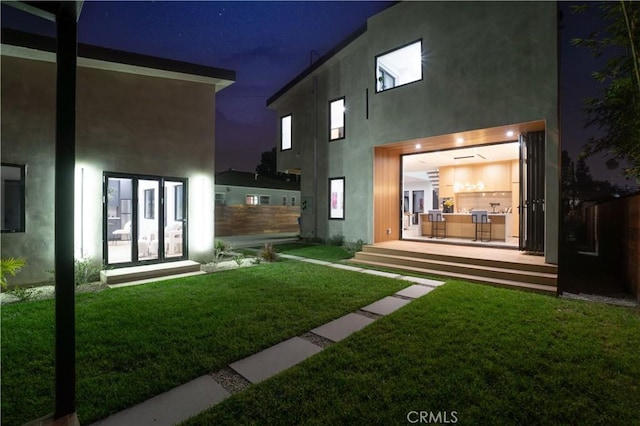 back house at night with a lawn and french doors