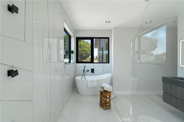 bathroom featuring tile patterned flooring, vanity, independent shower and bath, and tile walls