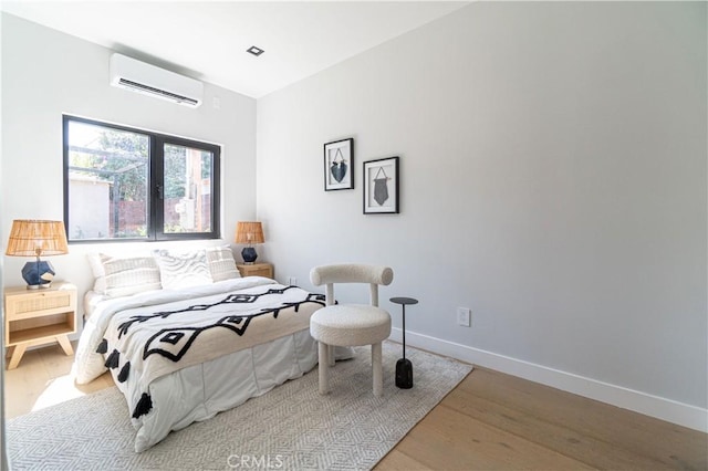 bedroom featuring a wall mounted AC and light hardwood / wood-style flooring