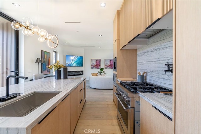 kitchen featuring pendant lighting, backsplash, sink, high end stainless steel range, and light hardwood / wood-style flooring