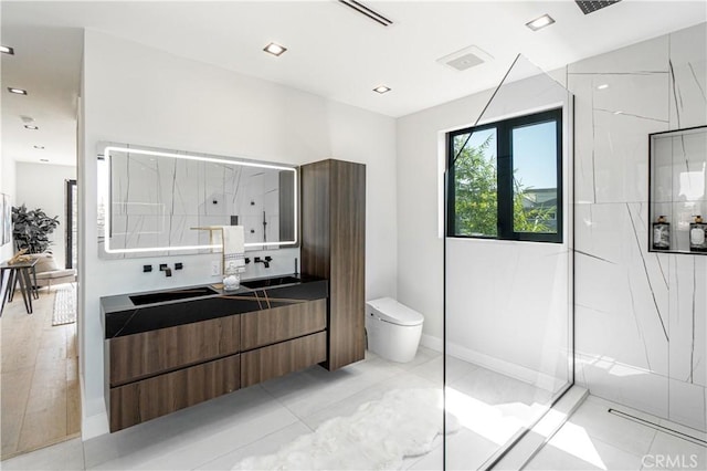 bathroom with tile patterned flooring, vanity, toilet, and tiled shower