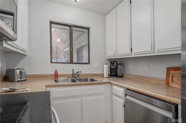 kitchen featuring appliances with stainless steel finishes, light countertops, white cabinetry, and a sink