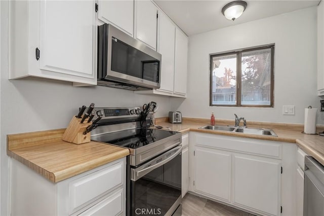 kitchen featuring appliances with stainless steel finishes, light countertops, a sink, and white cabinetry