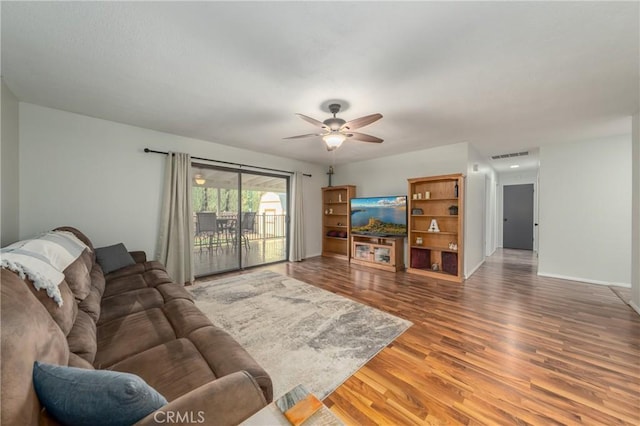 living room featuring baseboards, wood finished floors, visible vents, and a ceiling fan