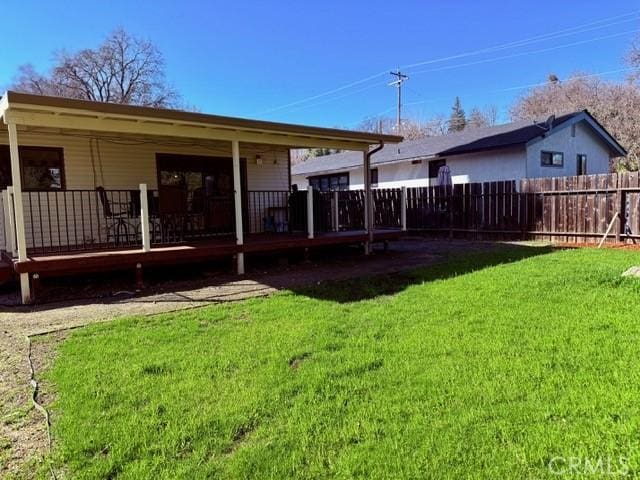 rear view of house featuring a yard and fence