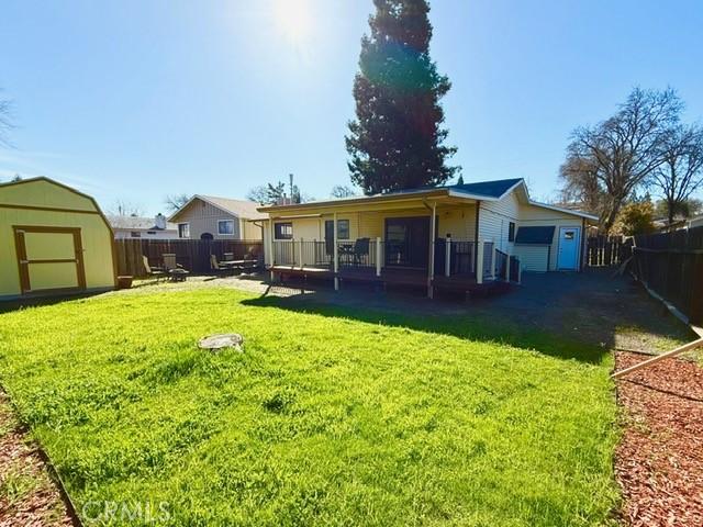 rear view of house with a yard, a fenced backyard, a storage unit, and an outdoor structure