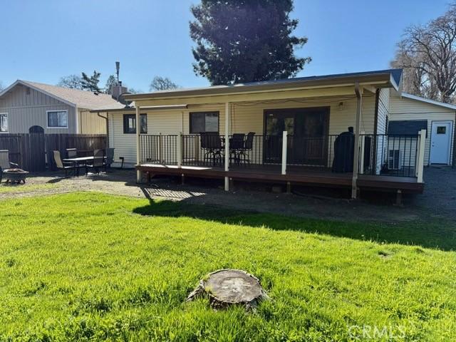 rear view of property featuring a lawn, a deck, and fence