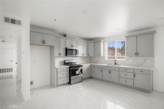 kitchen featuring backsplash, stainless steel appliances, gray cabinetry, and sink