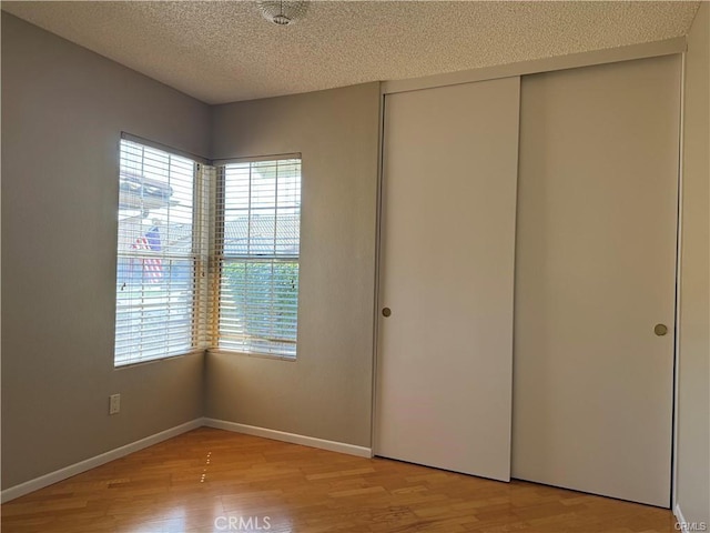 unfurnished bedroom featuring a closet, a textured ceiling, and light wood-type flooring