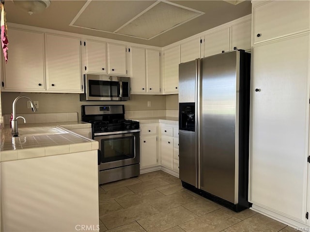 kitchen featuring tile counters, white cabinetry, sink, and appliances with stainless steel finishes