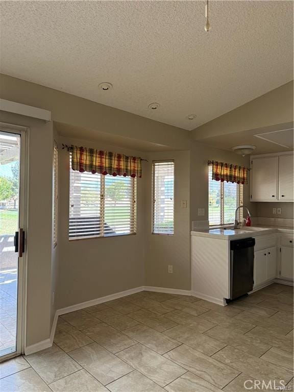 kitchen with lofted ceiling, white cabinetry, stainless steel dishwasher, and a textured ceiling