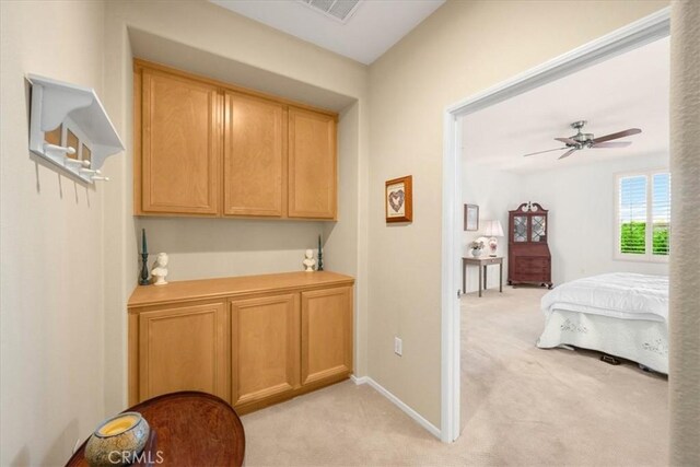 interior space featuring light brown cabinets, light colored carpet, and ceiling fan