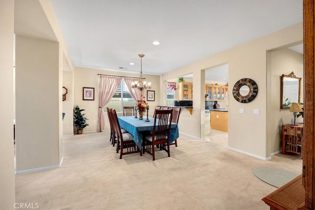 dining area with light colored carpet and an inviting chandelier