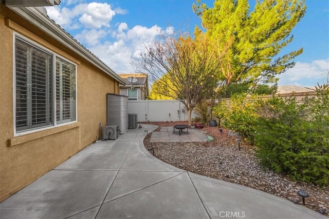 view of yard featuring a fire pit, cooling unit, and a patio area