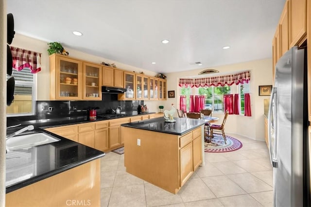 kitchen with decorative backsplash, sink, a center island, stainless steel refrigerator, and light tile patterned flooring