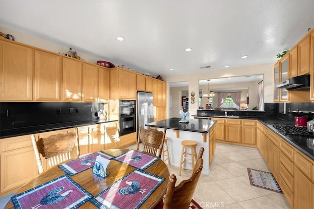 kitchen with sink, a center island, a kitchen bar, light tile patterned floors, and appliances with stainless steel finishes