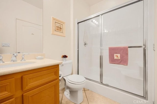 bathroom with tile patterned floors, vanity, a shower with shower door, and toilet