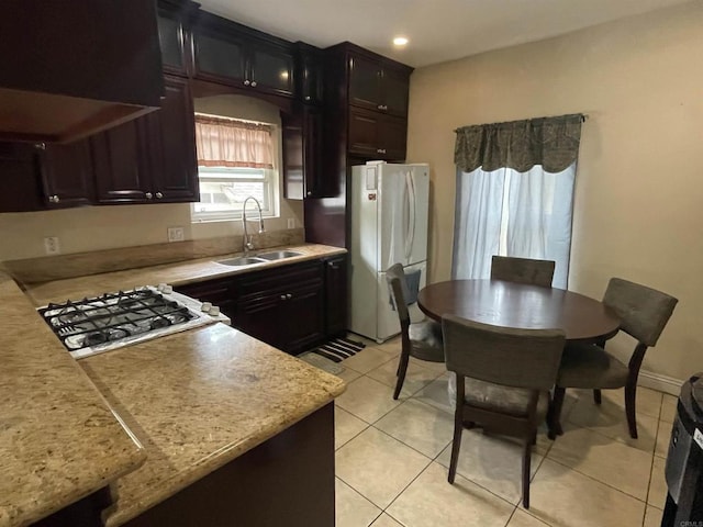 kitchen featuring dark brown cabinets, white appliances, sink, and light tile patterned floors