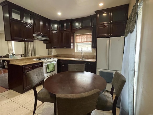 kitchen featuring light tile patterned flooring, white appliances, sink, and wooden counters