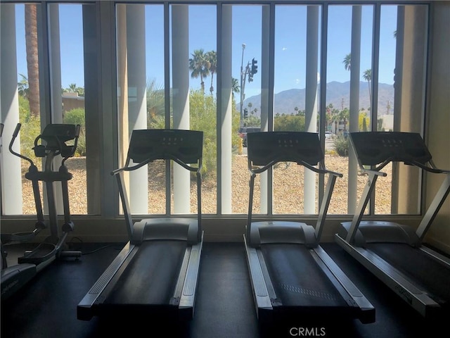 exercise room featuring a mountain view and a healthy amount of sunlight