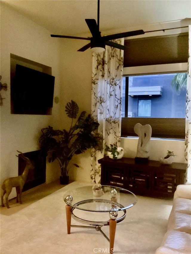 carpeted living room featuring a wall unit AC and ceiling fan