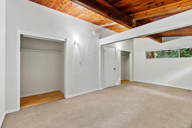 unfurnished bedroom featuring a closet, light carpet, wood ceiling, and vaulted ceiling with beams