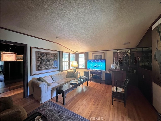 living room featuring lofted ceiling, a textured ceiling, ornamental molding, and wood finished floors