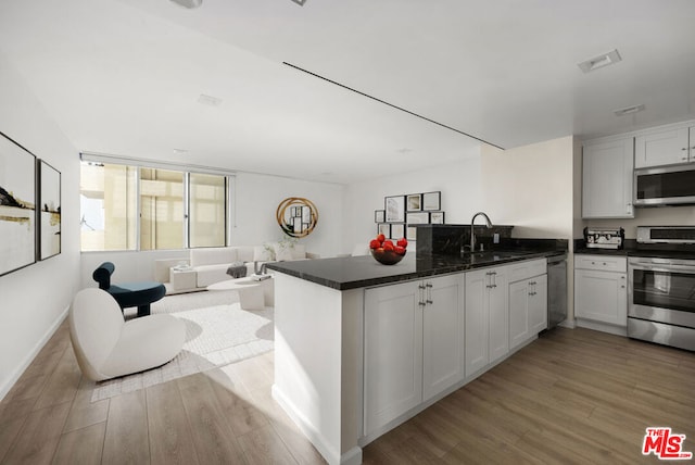 kitchen featuring white cabinets, kitchen peninsula, sink, and appliances with stainless steel finishes