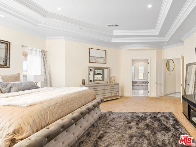 bedroom featuring connected bathroom, a tray ceiling, and ornamental molding