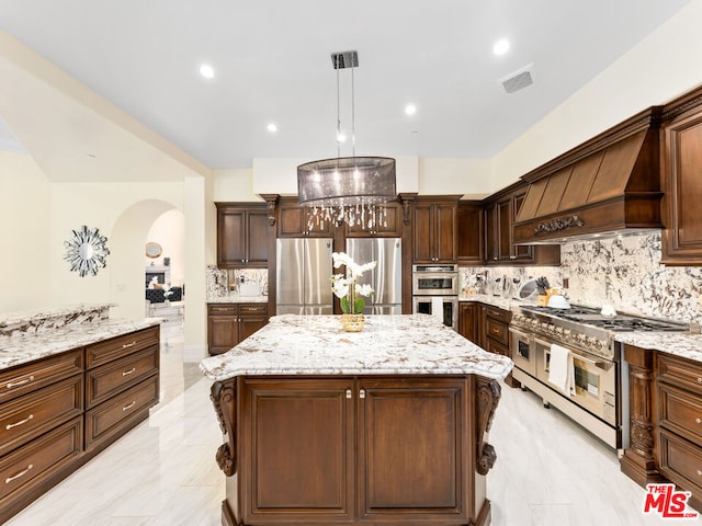 kitchen with backsplash, a center island, hanging light fixtures, appliances with stainless steel finishes, and custom range hood