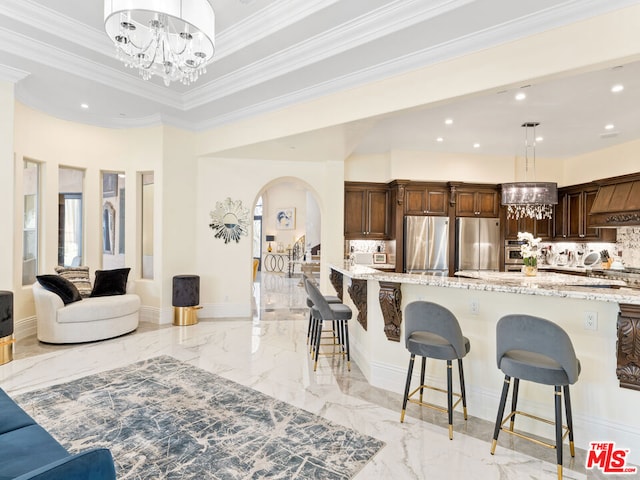 kitchen featuring light stone countertops, pendant lighting, stainless steel appliances, and a kitchen breakfast bar