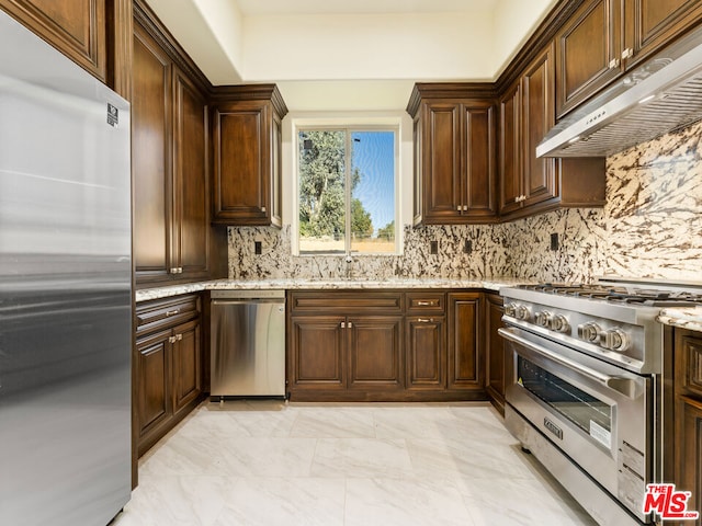 kitchen featuring light stone countertops, decorative backsplash, appliances with stainless steel finishes, and sink