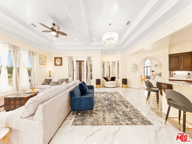 living room featuring ceiling fan with notable chandelier, a raised ceiling, and ornamental molding