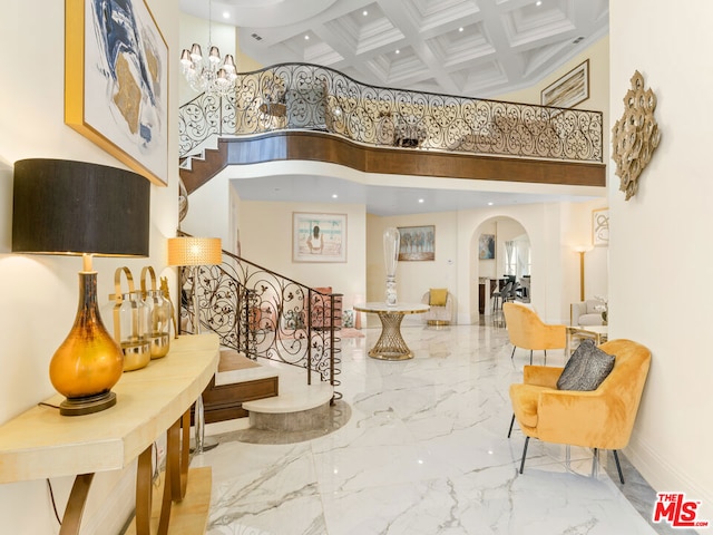 entrance foyer featuring a chandelier, beamed ceiling, a high ceiling, and coffered ceiling