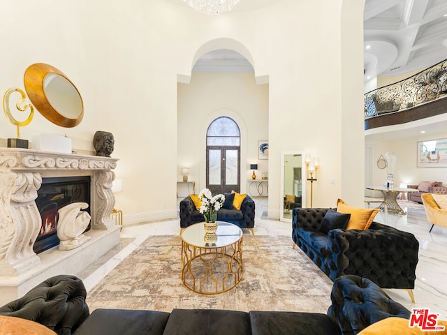 living room with a high ceiling, a high end fireplace, beamed ceiling, crown molding, and coffered ceiling