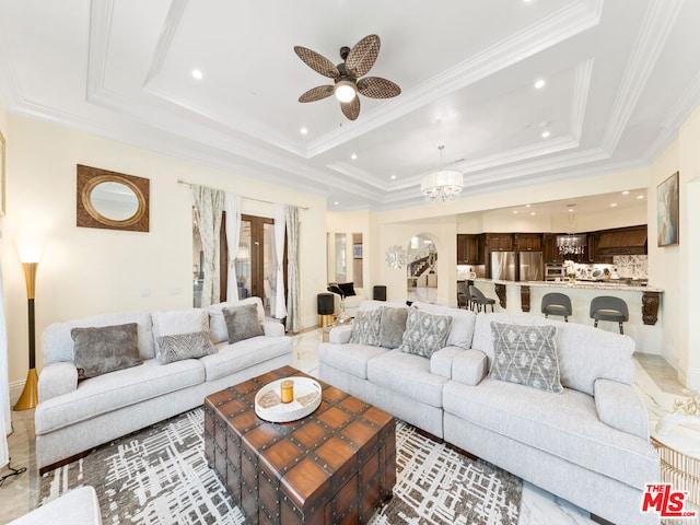 living room featuring a raised ceiling, crown molding, and ceiling fan with notable chandelier