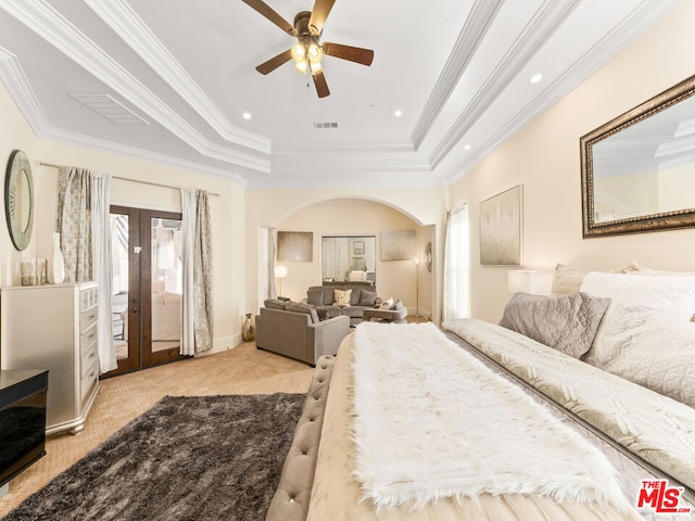 carpeted bedroom with ceiling fan, a tray ceiling, ornamental molding, and french doors