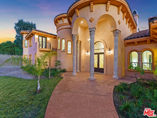 mediterranean / spanish-style home with french doors, a balcony, and a yard