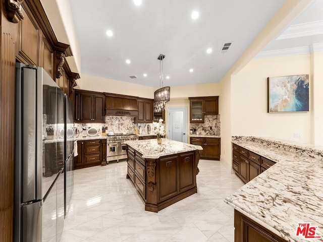 kitchen with stainless steel appliances, tasteful backsplash, a kitchen island, and decorative light fixtures