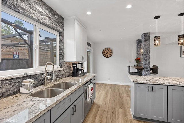 kitchen with gray cabinets, light stone countertops, light hardwood / wood-style floors, and sink