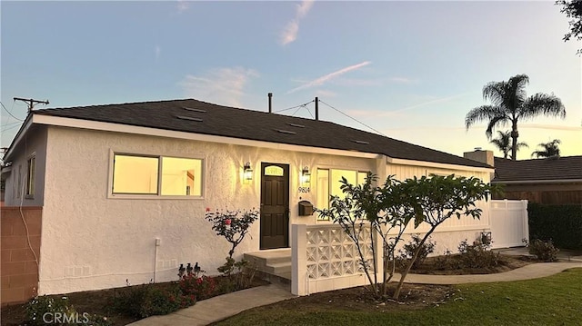 view of front of home with roof with shingles and fence