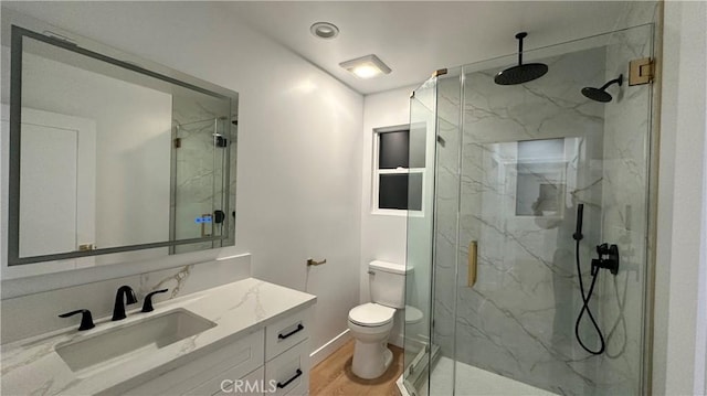 full bath featuring toilet, vanity, a marble finish shower, and wood finished floors