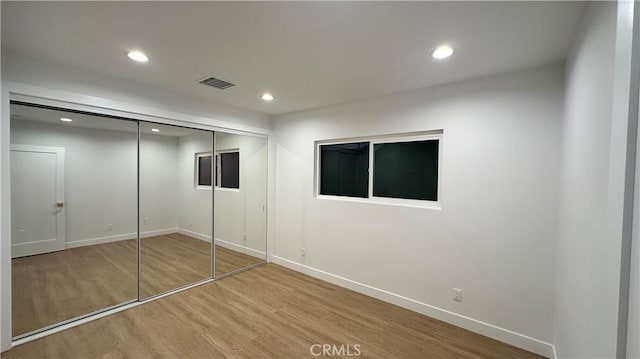 unfurnished bedroom featuring recessed lighting, a closet, visible vents, wood finished floors, and baseboards