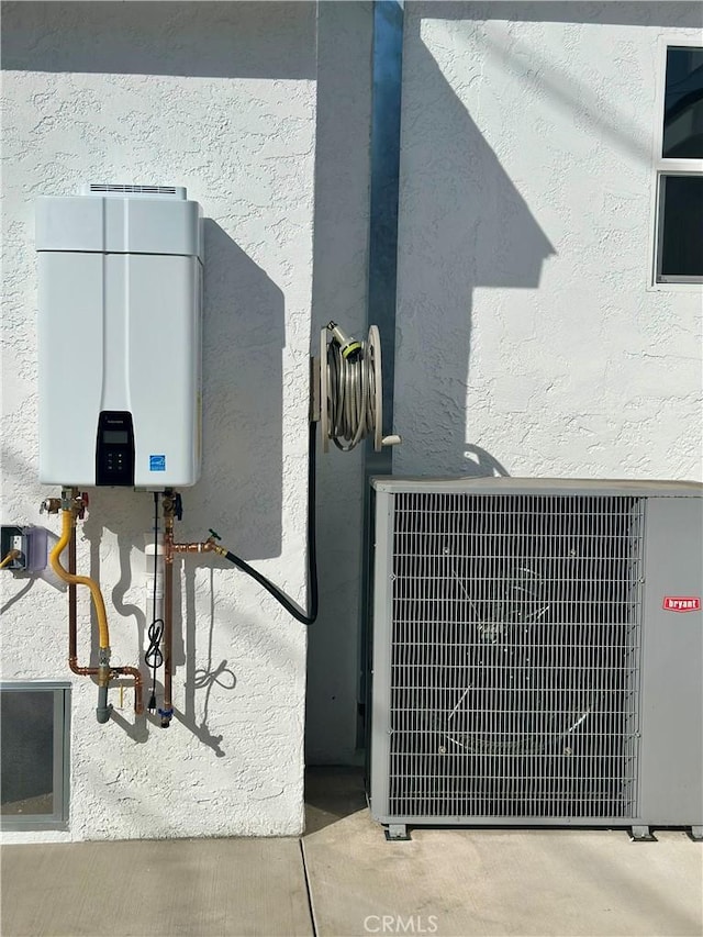 details with central AC unit, tankless water heater, and stucco siding