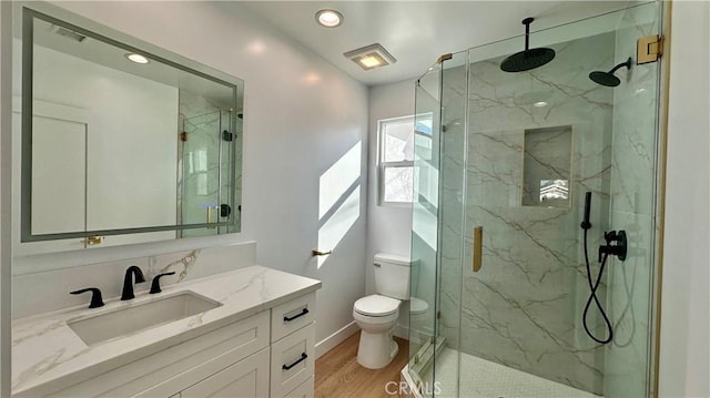 bathroom with toilet, vanity, a marble finish shower, and wood finished floors