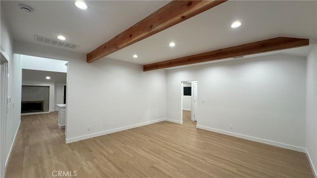 interior space featuring visible vents, light wood-style flooring, beamed ceiling, a fireplace, and recessed lighting