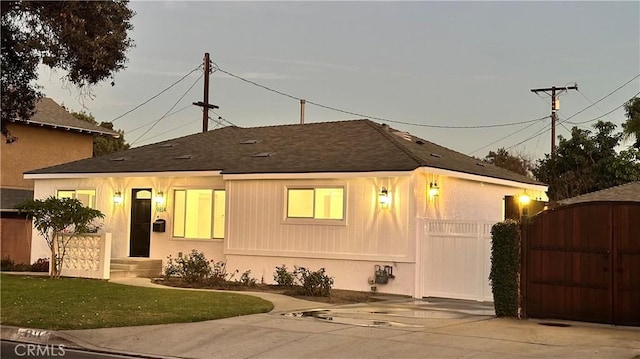 view of front of property featuring a shingled roof, fence, and a gate